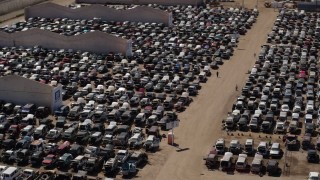 DX0002_136_040 - 5.7K aerial stock footage of orbiting cars at an automobile junkyard in Phoenix, Arizona