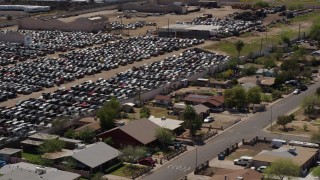 DX0002_136_044 - 5.7K aerial stock footage of an automobile junkyard beside urban homes in Phoenix, Arizona