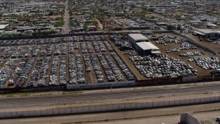 DX0002_137_009 - 5.7K aerial stock footage orbit and fly away from rows of cars at an automobile junkyard in Phoenix, Arizona