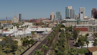 DX0002_137_036 - 5.7K aerial stock footage fly over palm trees at city park toward tall office buildings in Downtown Phoenix, Arizona