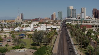 DX0002_137_038 - 5.7K stock footage aerial video flyby palm trees at city park and street leading to tall office buildings in Downtown Phoenix, Arizona