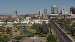 DX0002_137_039 - 5.7K aerial stock footage flying by city parks and a street leading to tall office buildings in Downtown Phoenix, Arizona