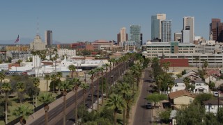 DX0002_137_040 - 5.7K aerial stock footage fly over city park palm trees toward tall office buildings in Downtown Phoenix, Arizona