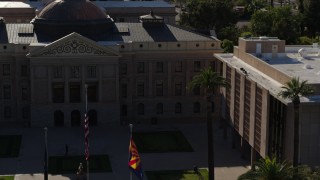DX0002_137_068 - 5.7K aerial stock footage fly away from flags in front of the Arizona State Capitol building in Phoenix, Arizona