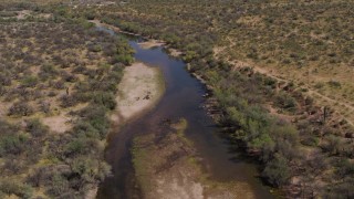 DX0002_141_005 - 5.7K aerial stock footage fly away from a group of horses beside a shallow desert river