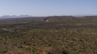 DX0002_141_033 - 5.7K aerial stock footage of panning across a desert road and hills