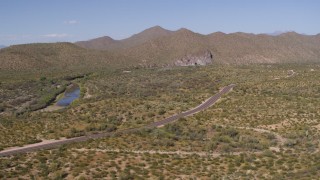DX0002_141_034 - 5.7K aerial stock footage of a desert road with light traffic with mountains in the background