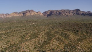 DX0002_141_035 - 5.7K aerial stock footage of flying by desert with green plants and cactus, bordered by mountains