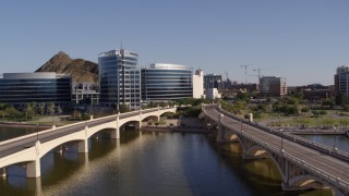 DX0002_142_012 - 5.7K aerial stock footage ascend and approach waterfront office buildings from bridges in Tempe, Arizona