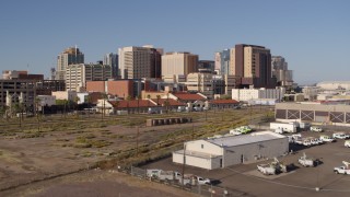 DX0002_142_021 - 5.7K aerial stock footage ascend and approach the city's skyline behind train station in Downtown Phoenix, Arizona