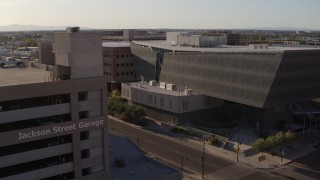 DX0002_142_035 - 5.7K aerial stock footage fly away from the Maricopa County Sheriff’s Office and parking garage at sunset in Downtown Phoenix, Arizona