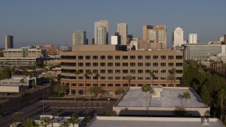 DX0002_143_006 - 5.7K aerial stock footage flying by state offices to reveal Adams Street leading to the city's skyline at sunset in Downtown Phoenix, Arizona