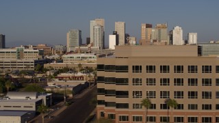 DX0002_143_008 - 5.7K aerial stock footage flying by state offices to reveal Adams Street leading to the city's skyline at sunset in Downtown Phoenix, Arizona