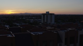 DX0002_143_053 - 5.7K aerial stock footage orbit apartment complex with the sun setting behind distant mountains, seen from Phoenix, Arizona