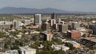 DX0002_144_035 - 5.7K aerial stock footage reverse view of tall office high-rises surrounded by city buildings in Downtown Tucson, Arizona