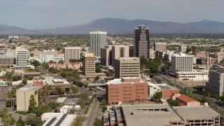 DX0002_144_038 - 5.7K aerial stock footage ascend and fly away from tall office high-rises surrounded by city buildings in Downtown Tucson, Arizona