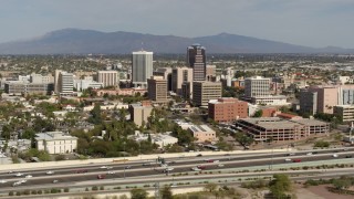 DX0002_144_039 - 5.7K aerial stock footage reverse view of tall office high-rises and city buildings, seen from I-10, Downtown Tucson, Arizona