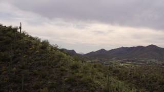 DX0002_145_002 - 5.7K aerial stock footage fly over small peak with cactus plants, reveals homes and golf course in Tucson, Arizona