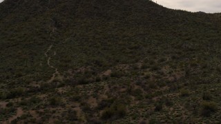 DX0002_145_008 - 5.7K aerial stock footage reverse view of a small peak with cactus plants in Tucson, Arizona