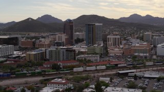 DX0002_145_037 - 5.7K aerial stock footage approach office towers as a train passes, with Sentinel Peak in the background, Downtown Tucson, Arizona