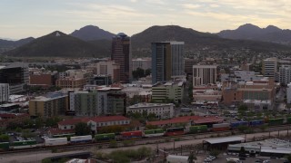 DX0002_145_038 - 5.7K aerial stock footage orbit office towers as a train passes, with Sentinel Peak in the background, Downtown Tucson, Arizona