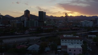 DX0002_146_044 - 5.7K aerial stock footage pass railroad tracks while focused on high-rise office towers at sunset in Downtown Tucson, Arizona