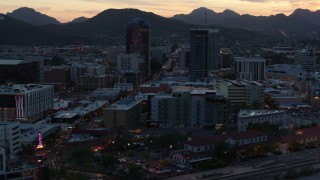 DX0002_147_012 - 5.7K aerial stock footage passing office towers at sunset with mountains in distance, Downtown Tucson, Arizona