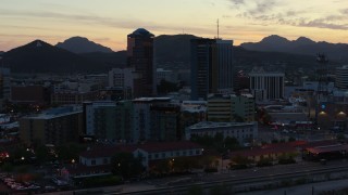 DX0002_147_013 - 5.7K aerial stock footage pass by office towers at sunset with mountains in background, Downtown Tucson, Arizona