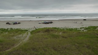 DX0002_148_004 - 4K aerial stock footage approach and ascend near groups of people on the beach in Long Beach, Washington