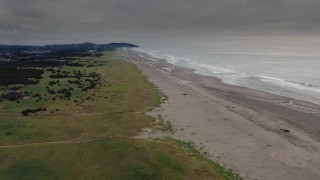 DX0002_148_020 - 4K aerial stock footage of a reverse view of beach-goers near the ocean in Long Beach, Washington