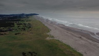 DX0002_148_023 - 4K aerial stock footage of a reverse view of groups of beach-goers near the ocean in Long Beach, Washington