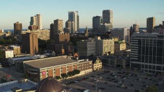 DX0002_150_022 - 5.7K aerial stock footage ascend away from college campus at sunset with view of city skyline, Downtown Milwaukee, Wisconsin