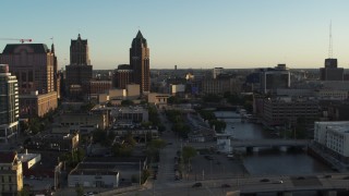 DX0002_150_026 - 5.7K aerial stock footage tall office tower and city buildings by the Milwaukee River at sunset, Downtown Milwaukee, Wisconsin