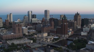 DX0002_150_029 - 5.7K aerial stock footage city buildings and skyscrapers seen from Milwaukee River at twilight, Downtown Milwaukee, Wisconsin