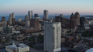 DX0002_150_030 - 5.7K aerial stock footage descend by apartment complex with view of downtown at twilight, Downtown Milwaukee, Wisconsin