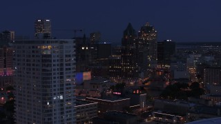 DX0002_151_004 - 5.7K aerial stock footage descend by apartment high-rise at night with view of office tower, Downtown Milwaukee, Wisconsin