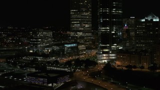 DX0002_157_037 - 5.7K aerial stock footage ascend and fly away from the base of a towering skyscraper at night, Downtown Milwaukee, Wisconsin