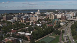DX0002_158_015 - 5.7K aerial stock footage ascend over lake with view of of apartment buildings near the capitol dome in Madison, Wisconsin
