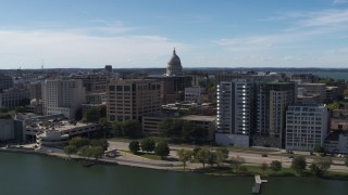 DX0002_158_029 - 5.7K aerial stock footage descend and fly away from the capitol dome surrounded by office buildings, Madison, Wisconsin