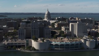 DX0002_160_002 - 5.7K aerial stock footage of the capitol seen while flying by office buildings and convention center, Madison, Wisconsin