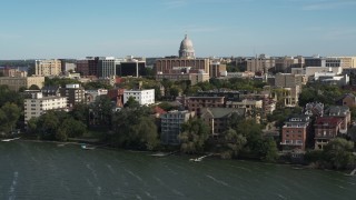 DX0002_160_026 - 5.7K aerial stock footage focus on the capitol dome while flying away from lakeside apartment buildings in Madison, Wisconsin