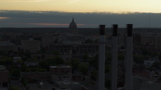 DX0002_162_006 - 5.7K aerial stock footage flyby smoke stacks with a view of the capitol dome at sunset, Madison, Wisconsin