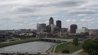 DX0002_165_018 - 5.7K stock footage aerial video ascend from park for view of skyline across the river, Downtown Des Moines, Iowa