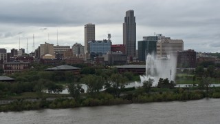 DX0002_169_019 - 5.7K aerial stock footage flying by a fountain and riverfront park with view of skyline, Downtown Omaha, Nebraska