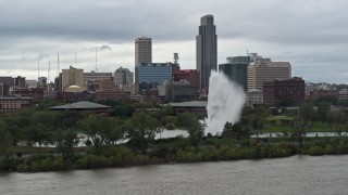DX0002_169_020 - 5.7K aerial stock footage passing by a fountain and riverfront park with view of skyline, Downtown Omaha, Nebraska