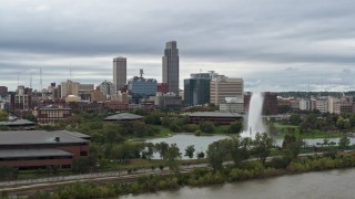 DX0002_169_026 - 5.7K aerial stock footage flying by a fountain in a park and skyline, Downtown Omaha, Nebraska