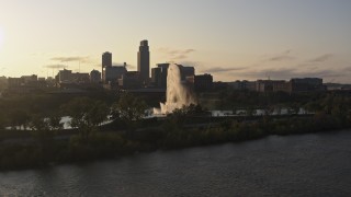 DX0002_172_006 - 5.7K aerial stock footage approach a fountain and riverfront park with view of skyline at sunset, Downtown Omaha, Nebraska