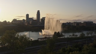 DX0002_172_007 - 5.7K aerial stock footage stationary view of a fountain with view of skyline at sunset, Downtown Omaha, Nebraska