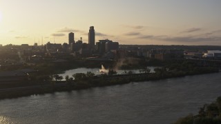 DX0002_172_009 - 5.7K aerial stock footage flying away from a fountain with view of skyline at sunset, Downtown Omaha, Nebraska