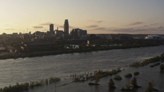 DX0002_172_010 - 5.7K aerial stock footage descend by river with view of a fountain and skyline at sunset, Downtown Omaha, Nebraska